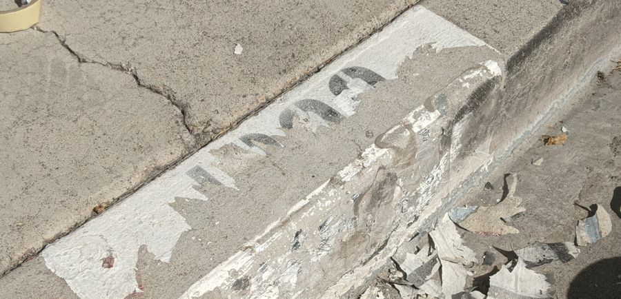 Banqueta con la pintura vieja raspada, pedazos de pintura en el suelo