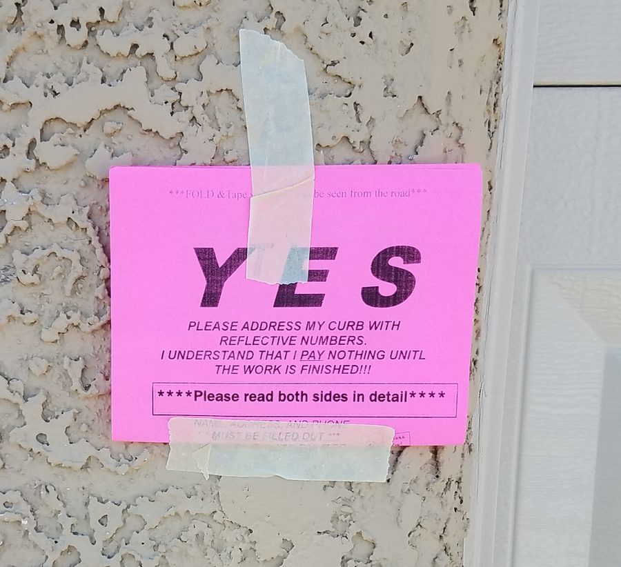 Pink YES flyer folded and taped to a garage so it faces the street