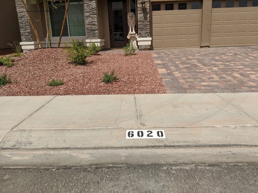 Painted curb number at the end of a driveway